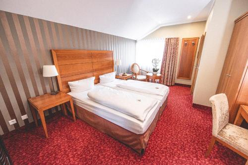 a hotel room with a large bed and a chair at PLAZA INN Recklinghausen in Recklinghausen