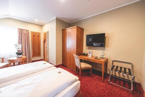 a hotel room with a bed and a desk with a television at PLAZA INN Recklinghausen in Recklinghausen