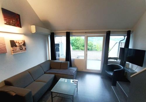 a living room with a couch and a table at Le Havre du Circuit / Triplex avec Sauna in Malmedy