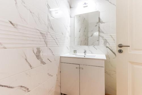 ein weißes Badezimmer mit einem Waschbecken und einem Spiegel in der Unterkunft Downtown Alfama & Me in Lissabon