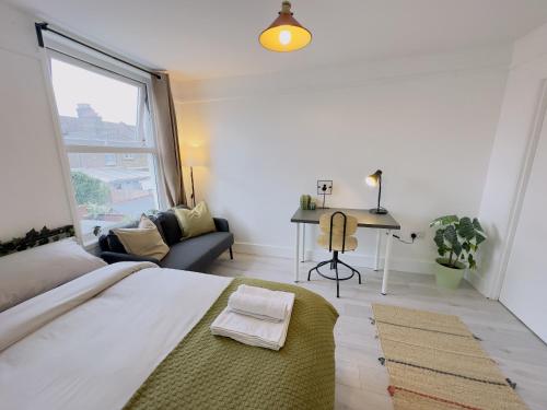 Schlafzimmer mit einem Bett, einem Schreibtisch und einem Fenster in der Unterkunft Leyton House - SleepyLodge in London