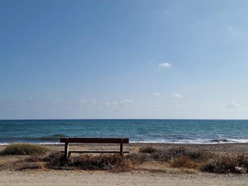 a bench sitting on the beach near the ocean at Mandria Villa in Paphos in Mandria