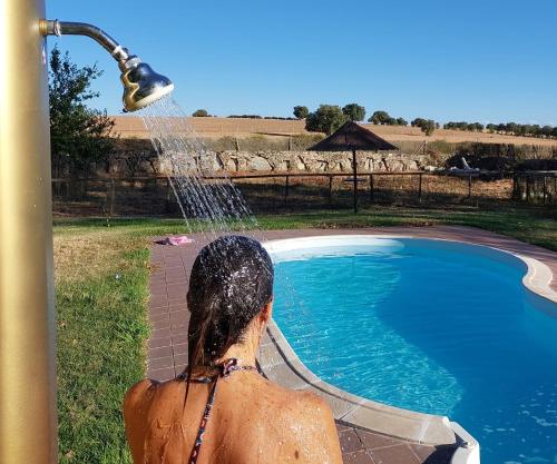 a woman standing under a water fountain next to a pool at Casa Atenea in Zamora