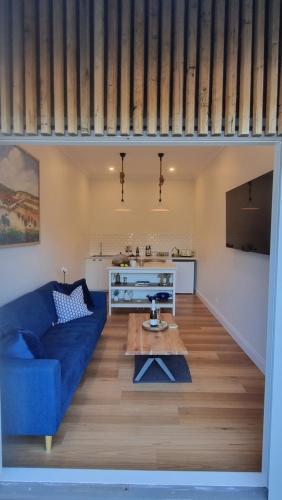 ein Wohnzimmer mit einem blauen Sofa und einem Tisch in der Unterkunft Winemakers Cottage at Treetops Red Hill in Red Hill