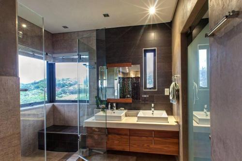 a bathroom with two sinks and a glass shower at The Beach House by African Watersports in Umkomaas