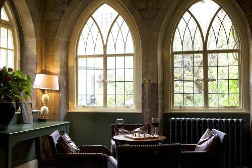 a restaurant with two windows and a table and chairs at The Manor House Hotel in Moreton in Marsh