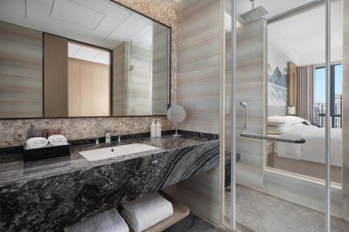 a bathroom with a sink and a mirror at Courtyard by Marriott Hangzhou Xiaoshan in Hangzhou