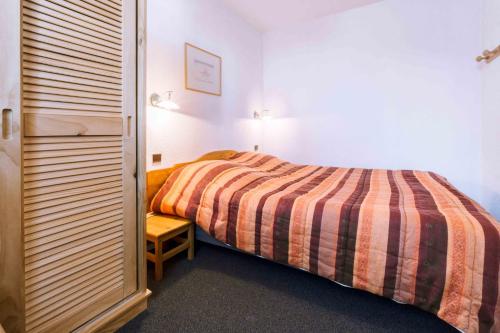 a bedroom with a bed with a striped blanket at Location Neron in Les Menuires