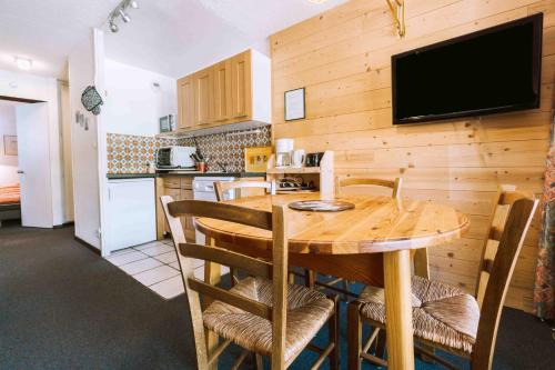 a kitchen and dining room with a wooden table and chairs at Location Neron in Les Menuires