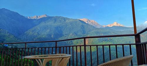 a balcony with two chairs and a view of mountains at Starlit Dome Mcleodganj in Dharamshala