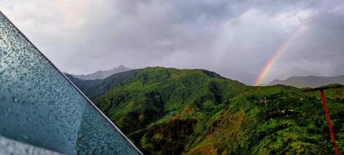 a rainbow in the sky over a mountain at Starlit Dome Mcleodganj in Dharamshala