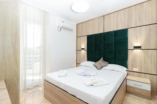 a bedroom with a large bed with a green headboard at Apartment Hotel Prego in Ulcinj