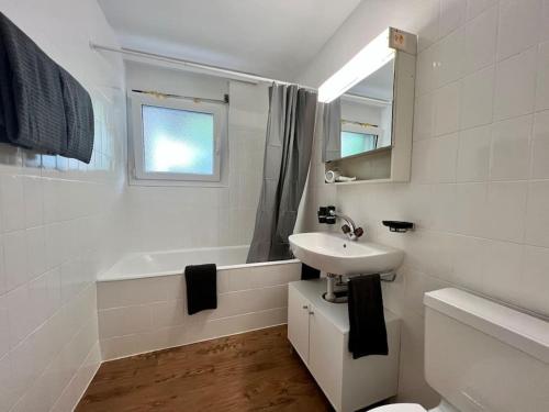 a white bathroom with a sink and a bath tub at Pure Comfort! Entire Apartment with Abundant Space near Zermatt in Täsch