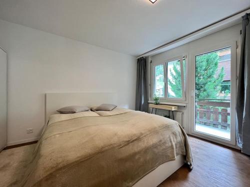a bedroom with a large bed and two windows at Pure Comfort! Entire Apartment with Abundant Space near Zermatt in Täsch