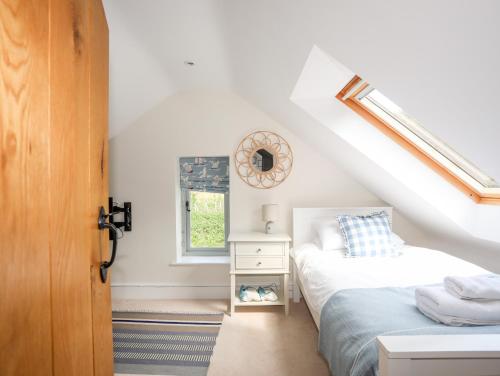 a attic bedroom with two beds and a window at Traeth Ora in Penrhos-Lligwy