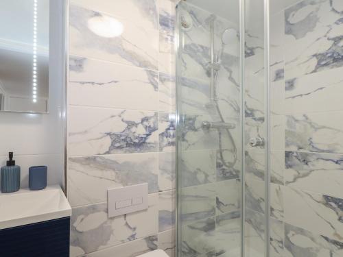 y baño con ducha y azulejos de mármol. en Harbour Studio en Penzance