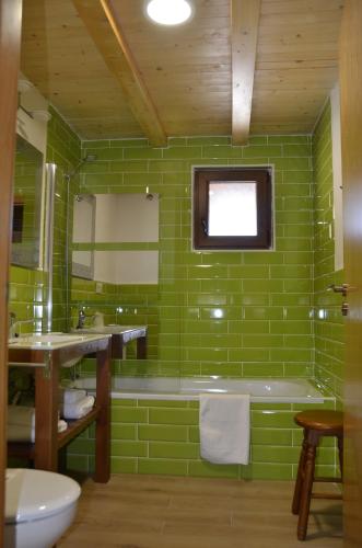 baño de azulejos verdes con bañera y ventana en Casa Atenea, en Zamora