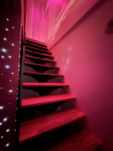 a staircase in a room with pink lighting at Le Bijou - Appartement, Sauna et Jacuzzi - Lille in Lille
