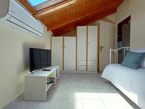 a bedroom with a bed and a flat screen tv at Doma Menidi Rooftop Apartment in Menídion