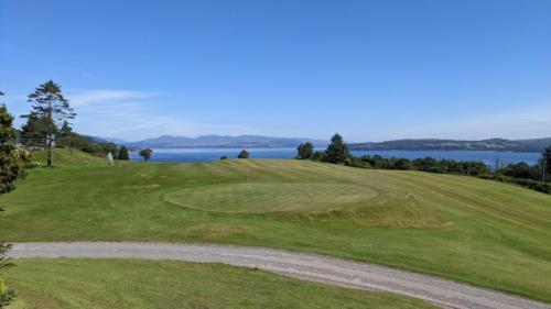 a view of a golf course with the ocean in the background at Beach House Pods in Dunoon