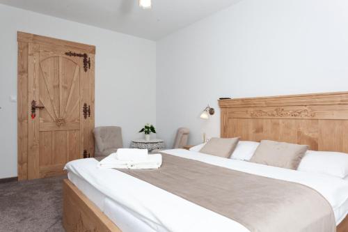 a bedroom with a large white bed with a wooden headboard at Drevenica u Pavla in Ždiar