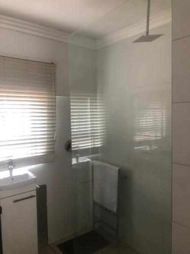a bathroom with a glass shower and a sink at Karaboapartlodge in Jane Furse