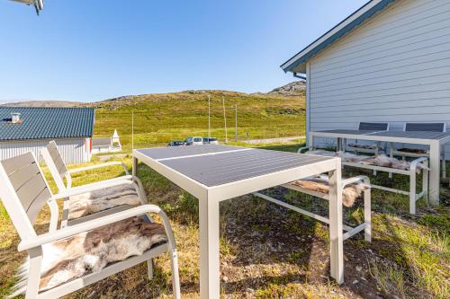 a picnic table and two chairs in front of a building at Arctic Lodging North Cape in Skarsvåg