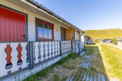 a house with a red door and a fence at Arctic Lodging North Cape in Skarsvåg