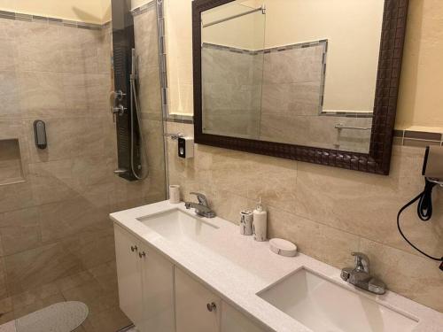 a bathroom with two sinks and a mirror at Luxury Comfy Penthouse Red hills in Kingston