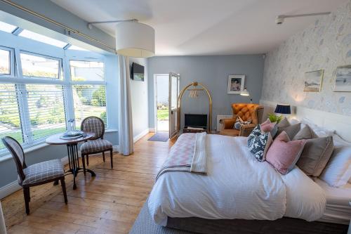 a bedroom with a large bed and a table and chairs at Roseville Youghal - Luxury Accommodation in Youghal
