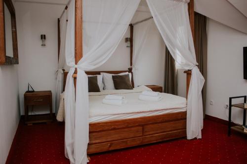 a bedroom with a canopy bed with white drapes at Hotel Serdar in Mojkovac