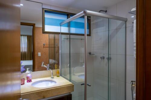ein Bad mit einem Waschbecken und einer Glasdusche in der Unterkunft Flat com 2 quartos e vista MAR da PRAIA de PONTANEGRA-wifi 200 mb-garagem-FAMÍLIA-Crianças-piscina-PET friendly in Natal