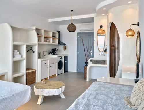 a white room with a bed and a table and a bathroom at Ocean View Paros in Parikia