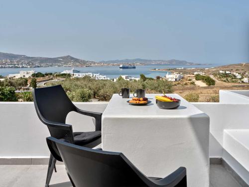 a white table with chairs and a bowl of fruit on it at Ocean View Paros in Parikia