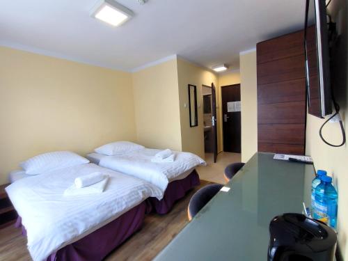 a hotel room with two beds and a desk at Arkadia in Kielce