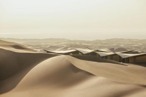 a desert scene with sand dunes and buildings at Six Senses Southern Dunes, The Red Sea in Khuff
