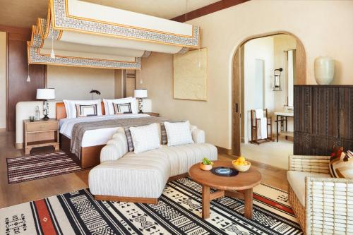 a bedroom with a bed and a couch and a table at Six Senses Southern Dunes, The Red Sea in Khuff
