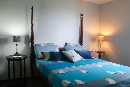 a bedroom with a bed with blue sheets and pillows at Alyzes Diamant in Le Diamant