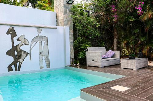 a swimming pool in a backyard with a painting on the wall at Alyzes Diamant in Le Diamant