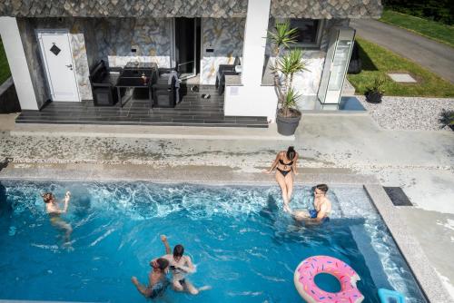 a group of people in a swimming pool with a pink donut at Resort TimAJA - pool, massage pool, sauna in Trebnje