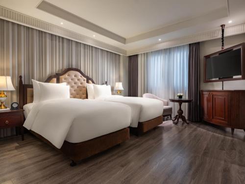 a hotel room with two beds and a flat screen tv at GRAND HOTEL du LAC Hanoi in Hanoi