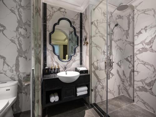 a bathroom with a sink and a shower with a mirror at GRAND HOTEL du LAC Hanoi in Hanoi