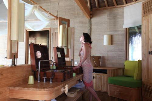 a woman walking in a room with a table at Six Senses Laamu in Laamu
