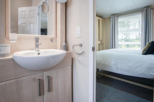 uma casa de banho com um lavatório e uma cama em 1 Manor Lodge - 3 Bedroom Lodge - Pendine em Pendine