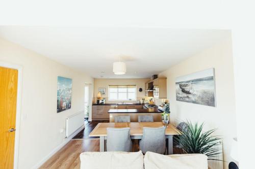 a kitchen and living room with a table and chairs at Luxury Trearddur Bay beach house with sea views in Trearddur