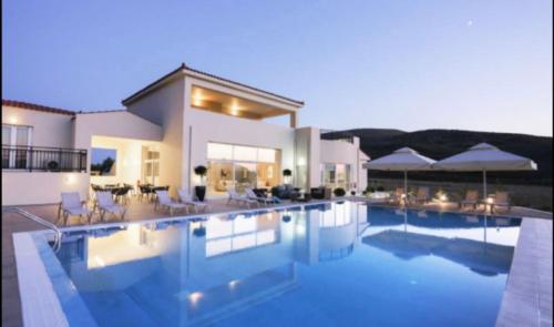 a large house with a swimming pool in front of it at Ammos Suites in Plati