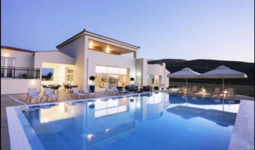 a large house with a swimming pool in front of it at Ammos Suites in Platy