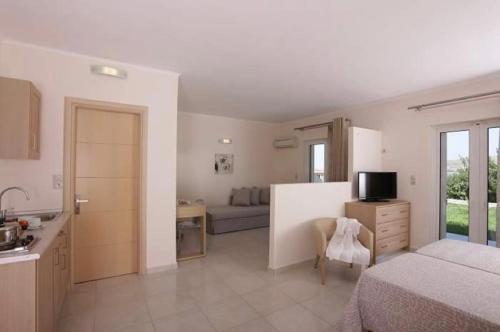 a bedroom with a bed and a kitchen with a couch at Ammos Suites in Plati