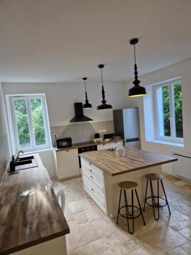 - une cuisine avec un îlot et deux tabourets de bar dans l'établissement Maison familiale de 280m², à Alboussière