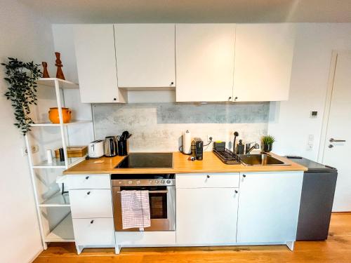 La cuisine est équipée de placards blancs et d'un four avec plaques de cuisson. dans l'établissement theSunset Club - STUDIO Küche - Balkon - Parken, à Memmingen